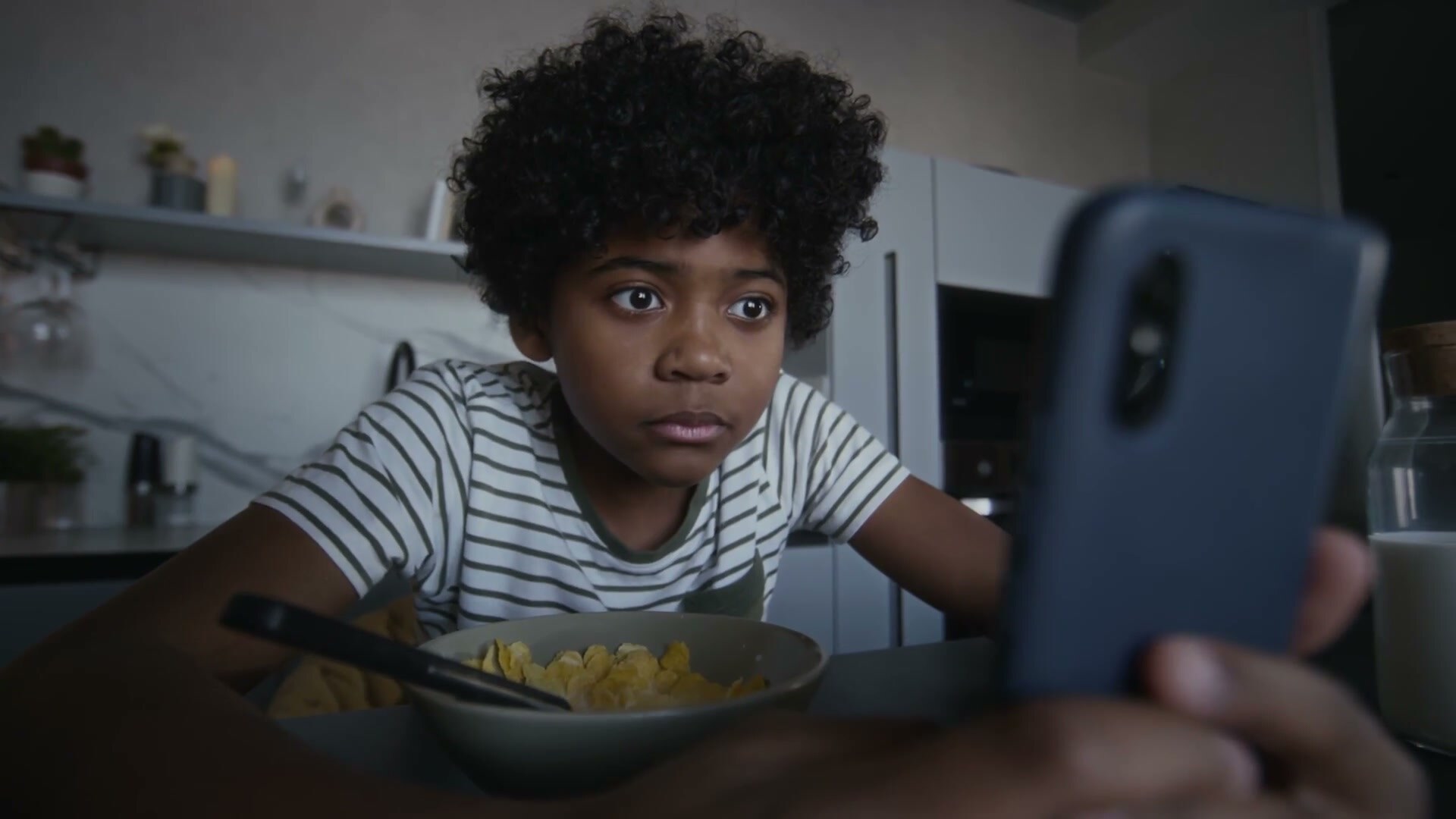 Schermgebruik brand film: kind met telefoon aan de ontbijttafel
